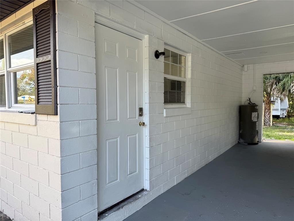 A white painted brick exterior wall features a door, a window, and a water heater — 5135-5129 UPSON AVENUE, DE LEON SPRINGS, FL