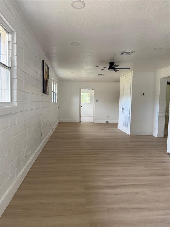 A bright living area features white block walls, light wood-look flooring, and a ceiling fan — 5135-5129 UPSON AVENUE, DE LEON SPRINGS, FL