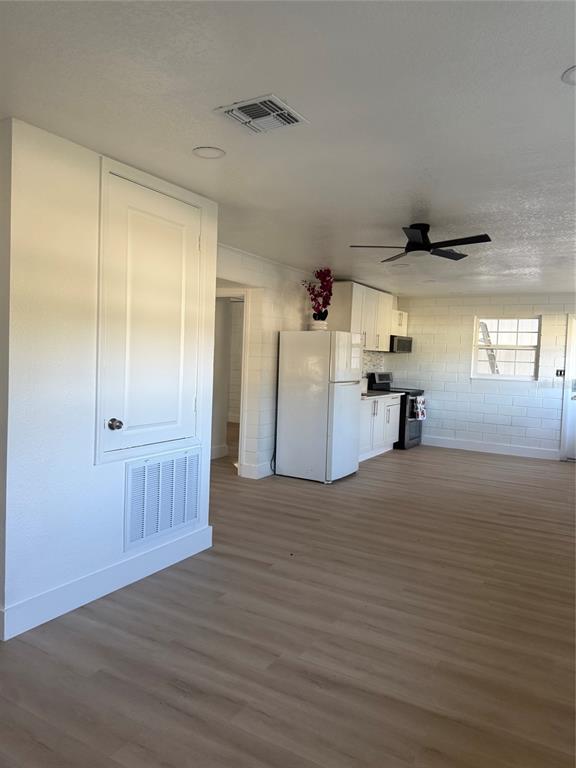 An open-concept kitchen and living area feature white block walls, light wood flooring, and cabinetry — 5135-5129 UPSON AVENUE, DE LEON SPRINGS, FL