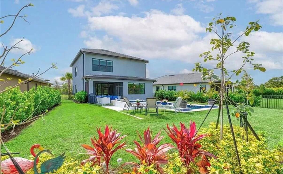 The backyard of a two-story house features a swimming pool, patio furniture, and landscaped gardens — 4688 E Pinehurst Trl Trail E, Oakland Park FL 33309, OAKLAND PARK, FL