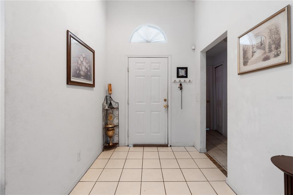 A tiled entryway features a white front door with a fanlight window and framed artwork — 5165 INNESBROOK COURT, ORLANDO, FL