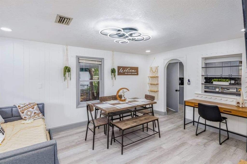 A dining area features a wooden table, bench, chairs, a desk, and a modern light fixture — 7524 MARIETTA STREET, ORLANDO, FL