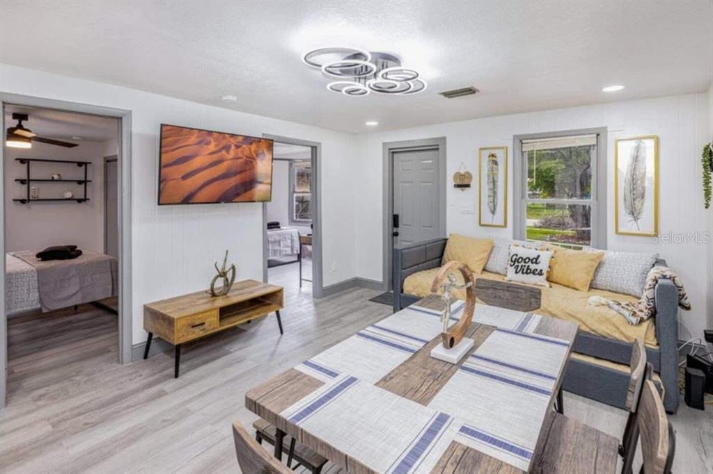 A living and dining area with light wood flooring, a television, and a daybed — 7524 MARIETTA STREET, ORLANDO, FL