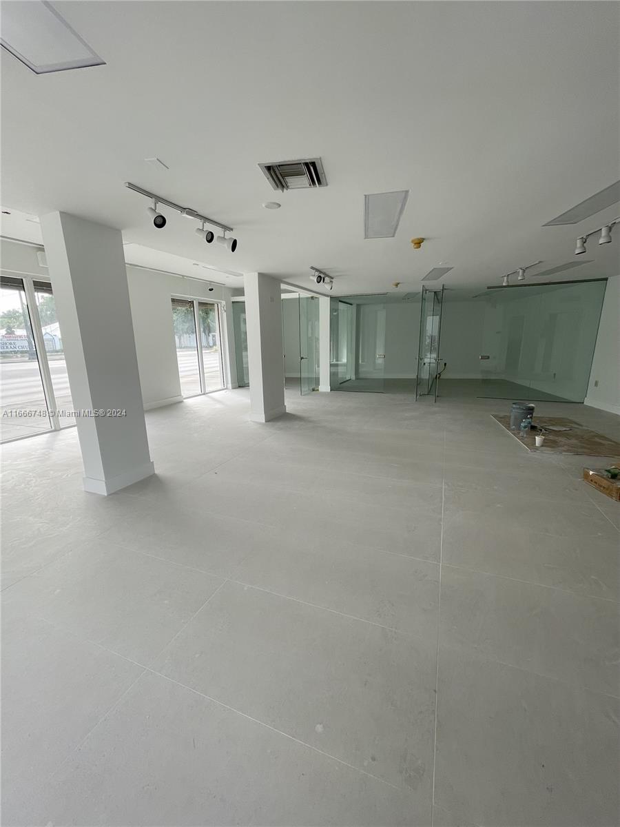 An open-plan commercial space features white tiled floors, glass-walled offices, and track lighting — 5050 Biscayne Blvd # 100, Miami FL 33137, MIAMI, FL