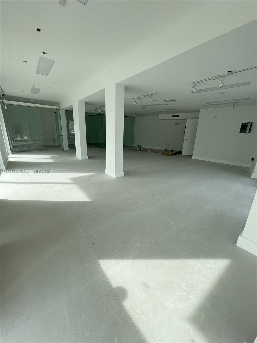 An open-plan interior space features white walls, large light-colored floor tiles, and structural columns — 5050 Biscayne Blvd # 100, Miami FL 33137, MIAMI, FL