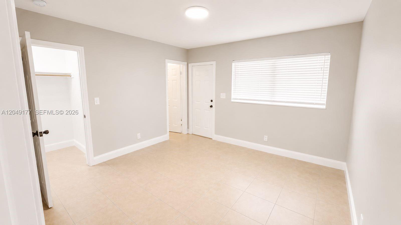 A bedroom with light gray walls, tile flooring, a closet, and a white door — 2332 Roosevelt St # 32, Hollywood FL 33020, HOLLYWOOD, FL
