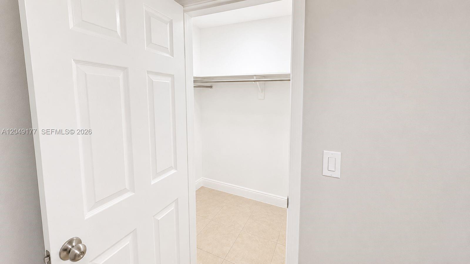 A white door opens into a small walk-in closet with tiled flooring and shelving — 2332 Roosevelt St # 32, Hollywood FL 33020, HOLLYWOOD, FL