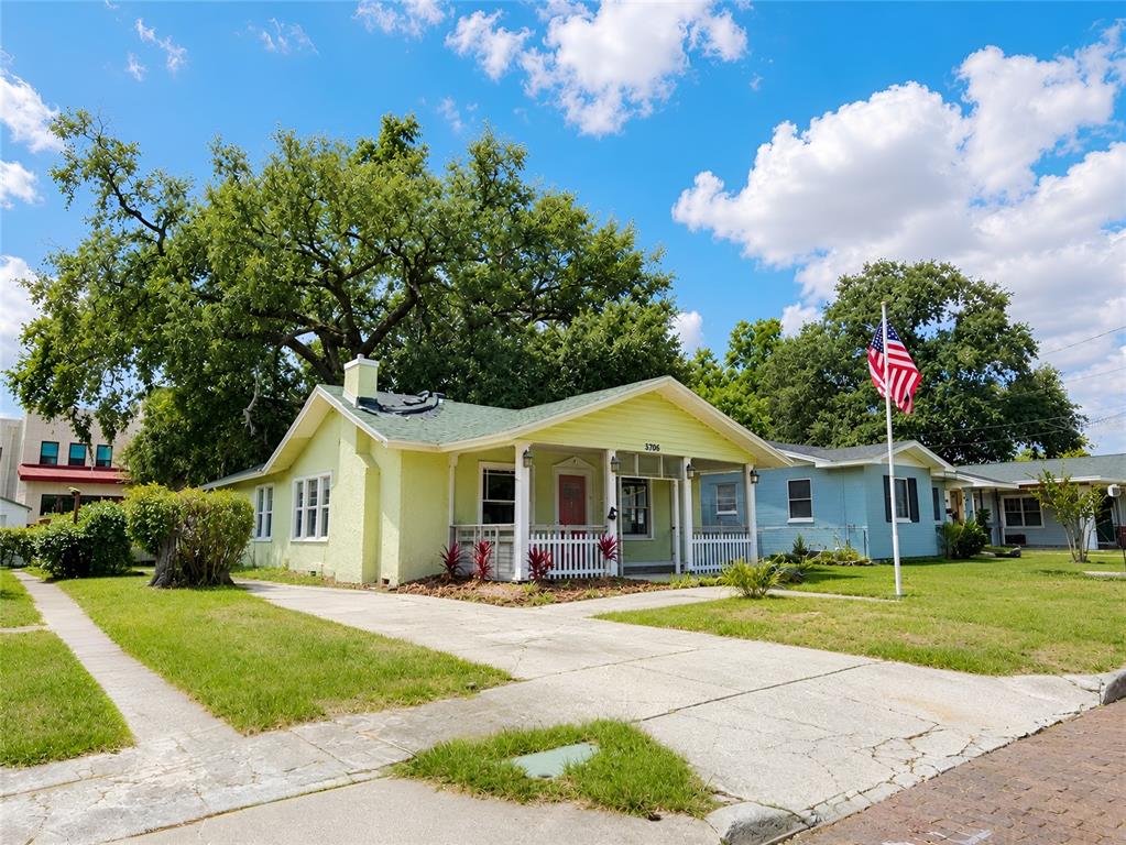 A yellow single-story house with a front porch and an American flag in the yard — 1037 LEXINGTON STREET, LAKELAND, FL