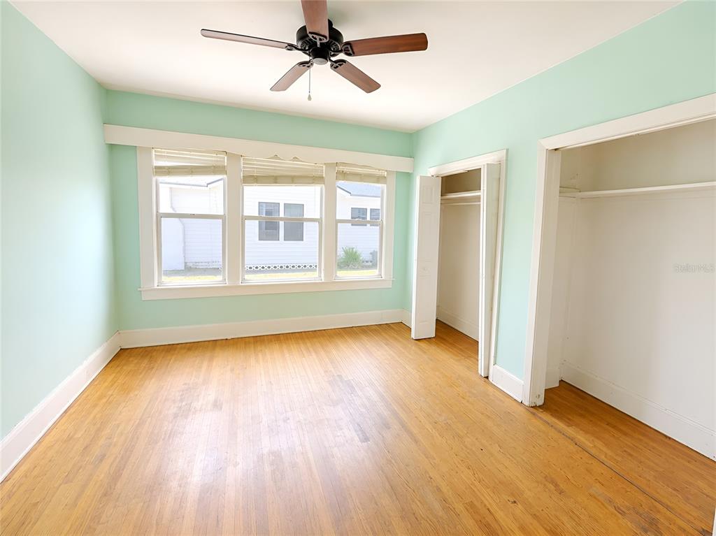 An empty bedroom features light green walls, hardwood floors, a ceiling fan, and two closets — 1037 LEXINGTON STREET, LAKELAND, FL