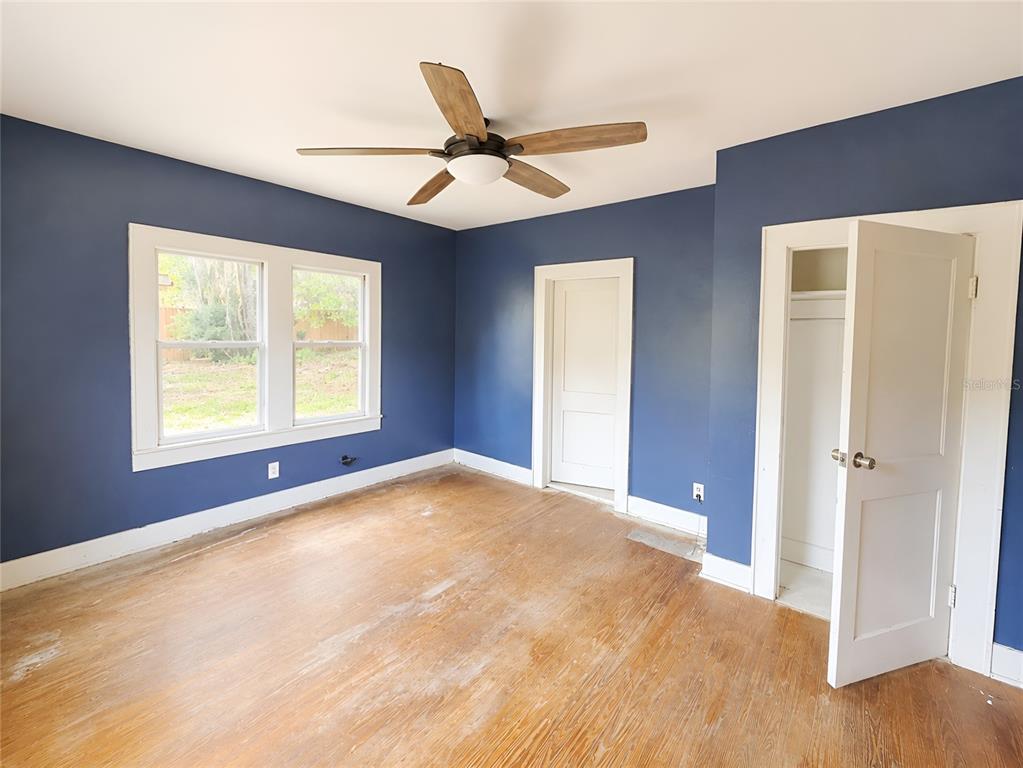 An empty bedroom features blue walls, hardwood floors, a ceiling fan, and two white doors — 1037 LEXINGTON STREET, LAKELAND, FL