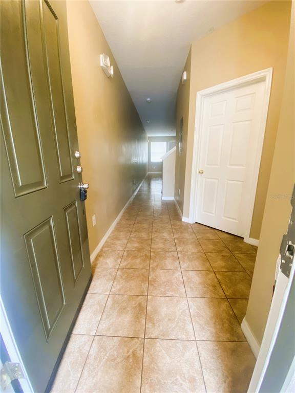 A tiled entryway leads to a long hallway with a white door on the right — 7602 LONG ISLAND DRIVE, KISSIMMEE, FL