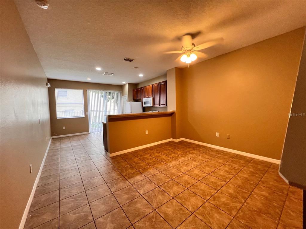 An open-concept living and dining area features tile flooring, a breakfast bar, and kitchen cabinetry — 7602 LONG ISLAND DRIVE, KISSIMMEE, FL