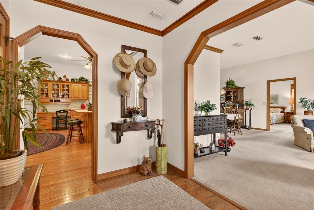A foyer with a console table and hats leads to a kitchen and living area — 5174 NE 7TH PLACE, OCALA, FL