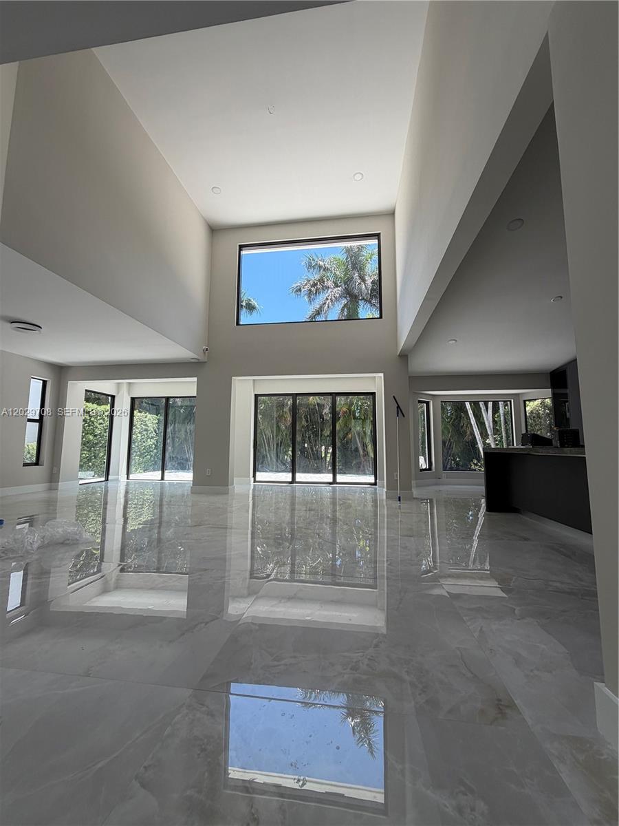 A spacious, modern living room features high ceilings, large windows, and polished marble flooring — 4499 NW 93rd Doral Ct, Doral FL 33178, DORAL, FL