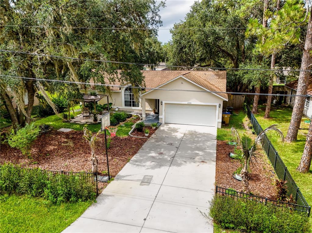An aerial view of a single-story house with a driveway, basketball hoop, and landscaped yard — 6449 ADAM STREET, ST CLOUD, FL