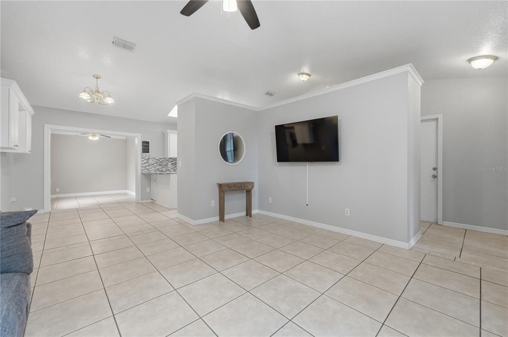 A living room with light gray walls, tile flooring, and a wall-mounted television — 6449 ADAM STREET, ST CLOUD, FL