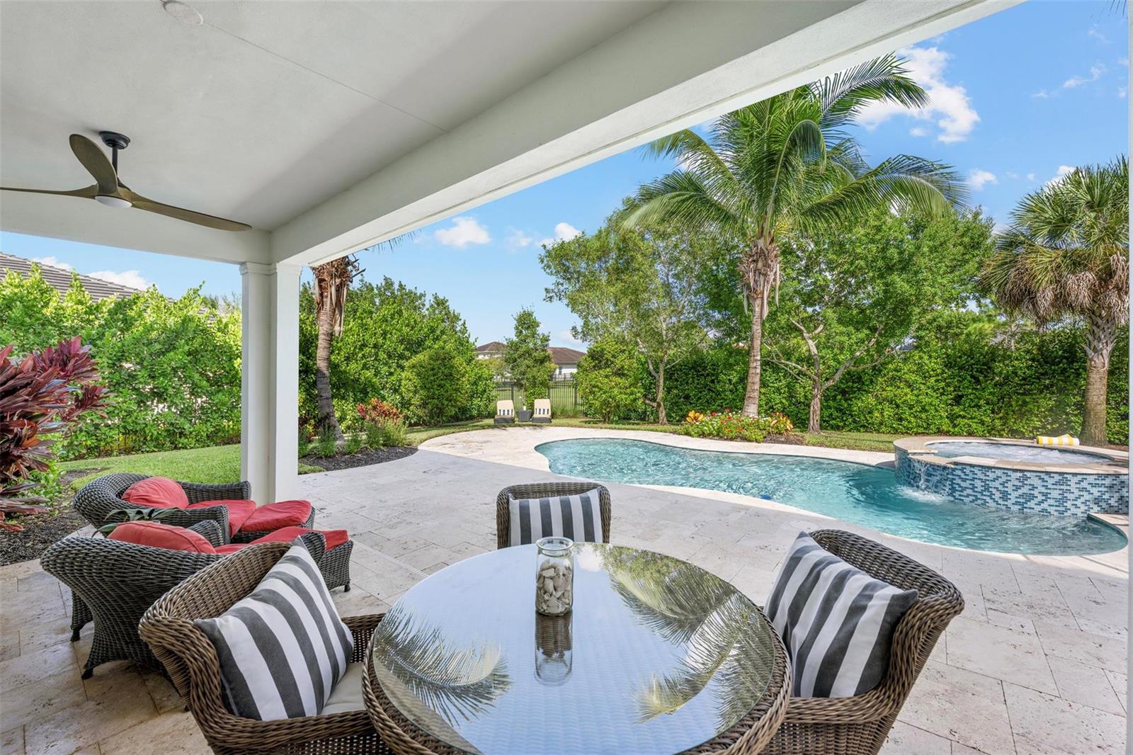 A covered patio features wicker furniture, a glass-top table, and a pool with a spa — 1018 Sweetgrass Street, Loxahatchee FL 33470, LOXAHATCHEE, FL