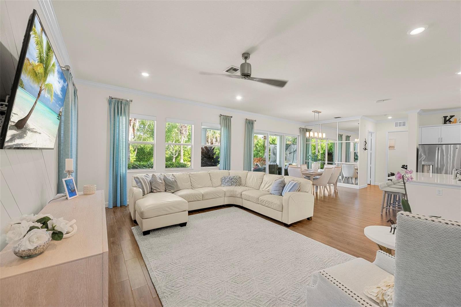 A bright living room features a white sectional sofa, light wood floors, and a ceiling fan — 1018 Sweetgrass Street, Loxahatchee FL 33470, LOXAHATCHEE, FL