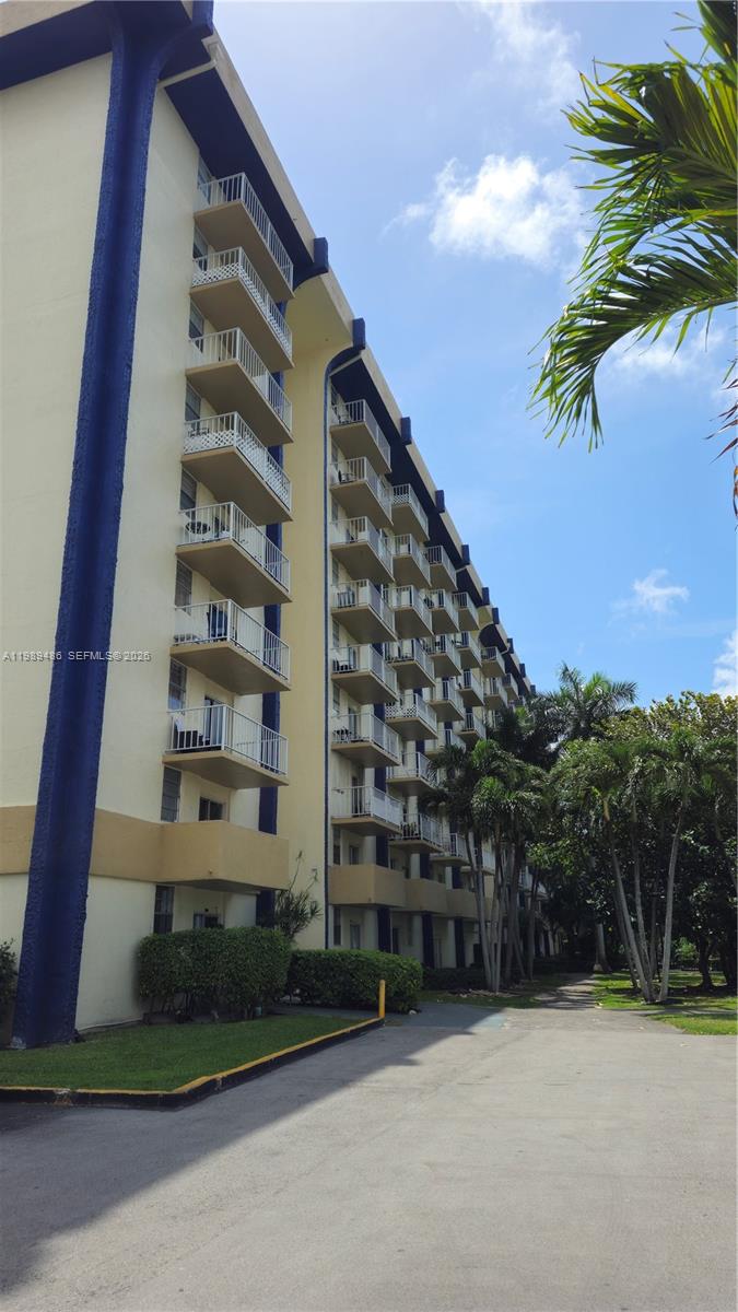 A multi-story apartment building features stacked balconies and blue vertical accents against a blue sky — 4550 NW 9th St # 505E, Miami FL 33126, MIAMI, FL