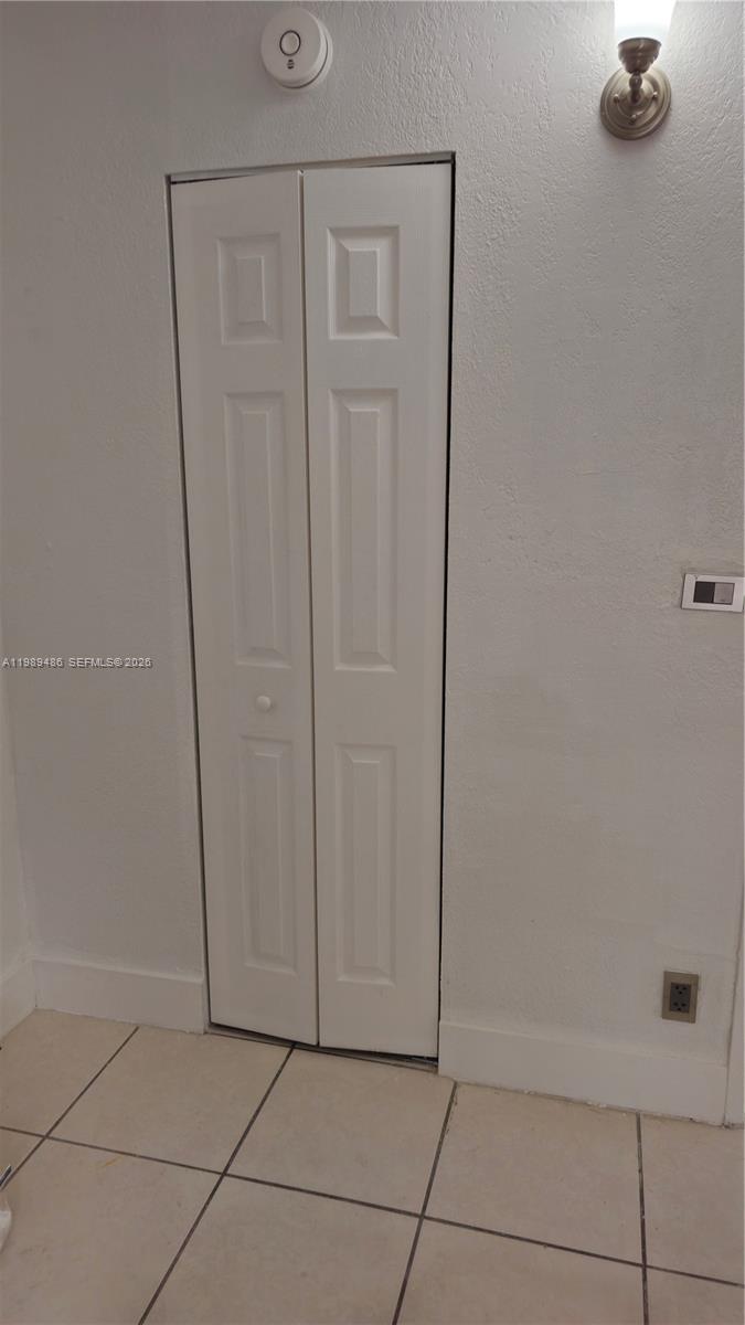 A white bi-fold closet door is set into a wall with tile flooring — 4550 NW 9th St # 505E, Miami FL 33126, MIAMI, FL