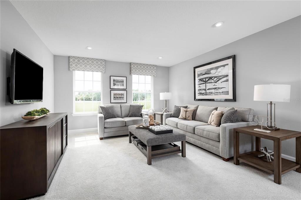 A living room features gray walls, carpeted flooring, a sofa, a loveseat, and a television — 1658 W PALMS DRIVE, PORT CHARLOTTE, FL