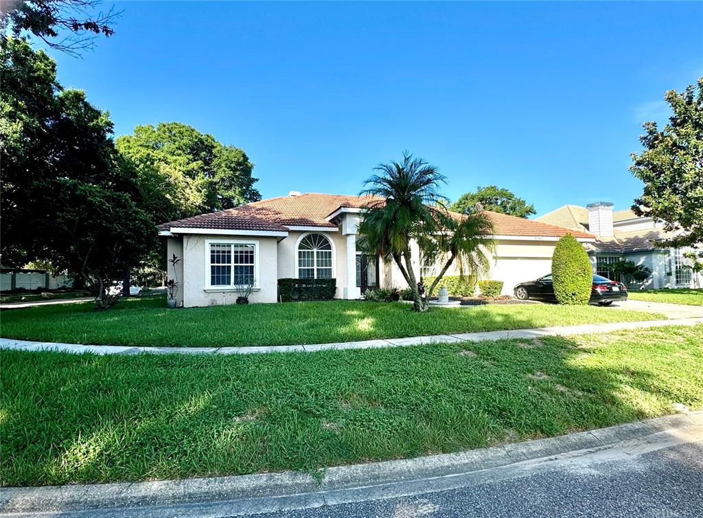 A single-story house with a tiled roof, palm tree, and lawn viewed from the street — 9042 SHAWN PARK PLACE, ORLANDO, FL