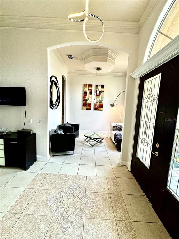 An entryway leads to a living area with tile flooring, modern lighting, and dark furniture — 9042 SHAWN PARK PLACE, ORLANDO, FL