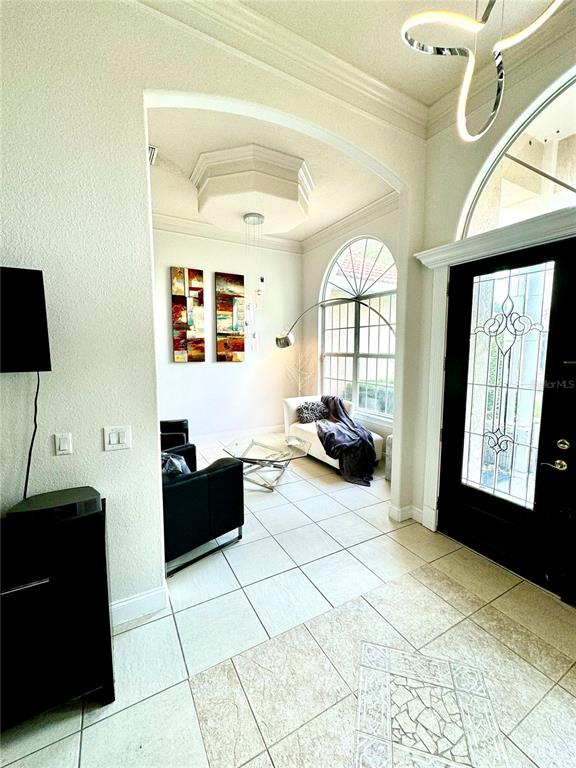 A bright entryway features tiled floors, a modern light fixture, and a view into a living area — 9042 SHAWN PARK PLACE, ORLANDO, FL