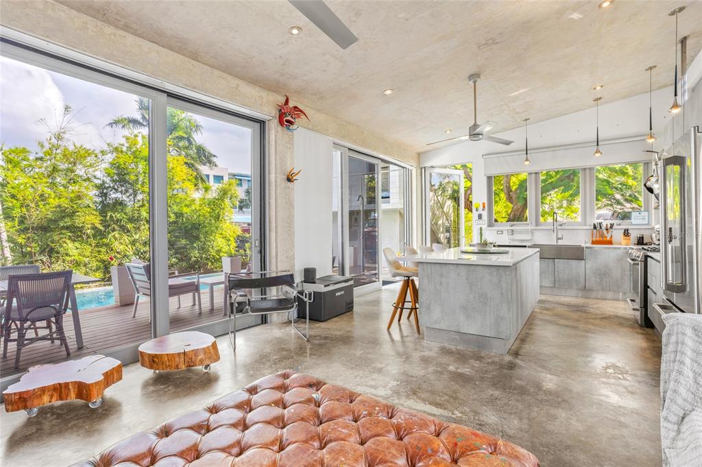 A modern open-concept kitchen and living area with concrete floors, an island, and sliding doors — PR 413 SOLAR C BO. PUNTAS, RINCON, PR