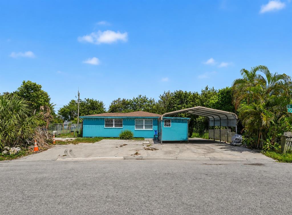 A single-story turquoise house with a metal carport stands behind a concrete driveway — 2839 19TH STREET W, BRADENTON, FL