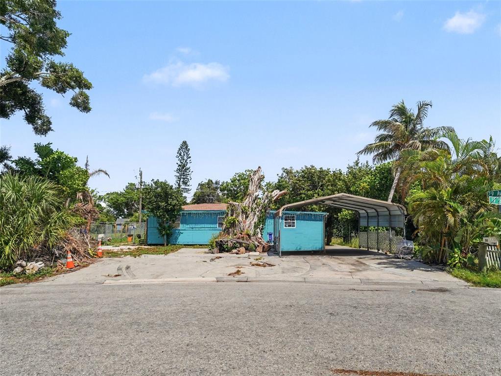 A blue single-story house with a carport sits on a paved lot with trees — 2839 19TH STREET W, BRADENTON, FL