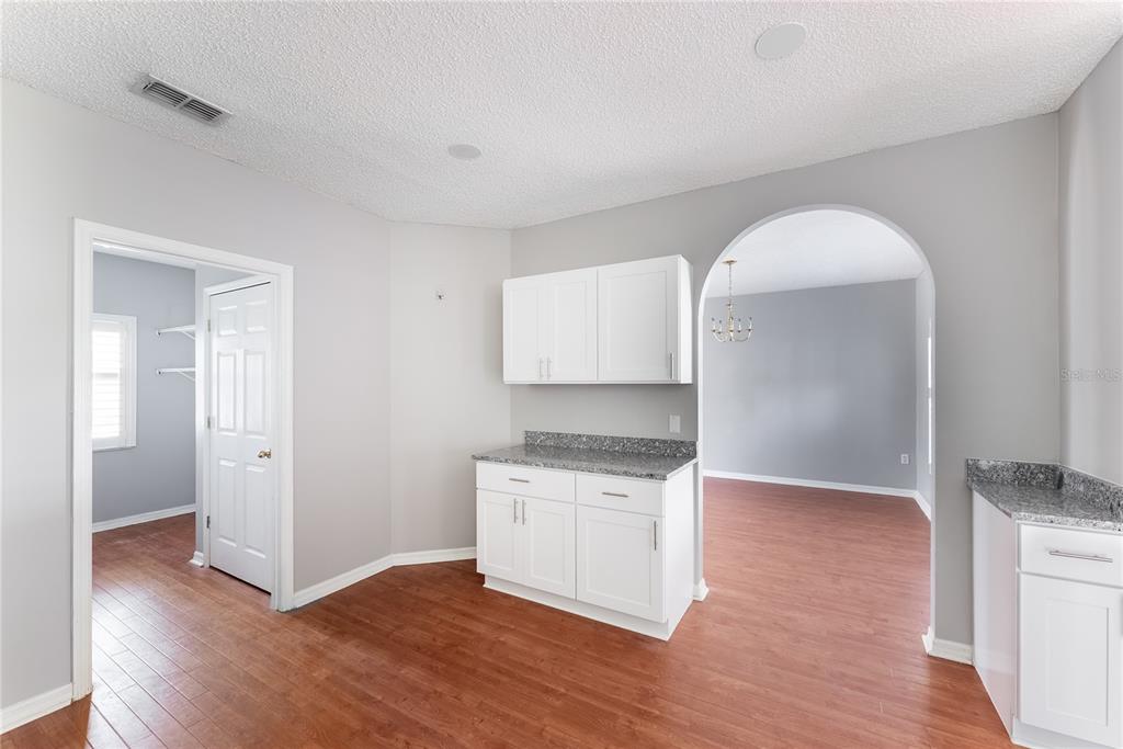 A kitchen area features white cabinets, granite countertops, and wood-look flooring with an arched doorway — 234 BALBOA DRIVE, KISSIMMEE, FL