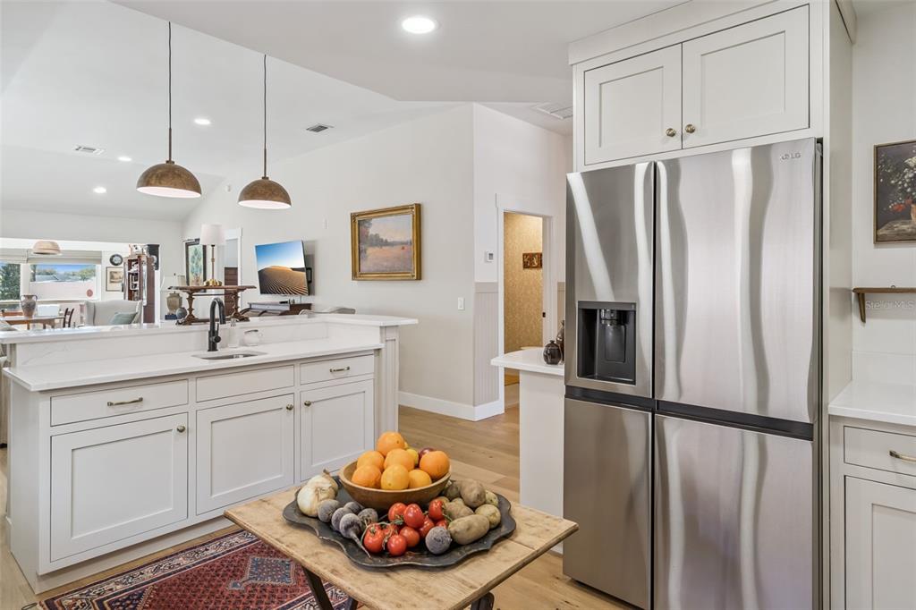 A kitchen features white cabinets, stainless steel appliances, and a wooden island with produce — 1304 SANTA ROSA COURT, THE VILLAGES, FL