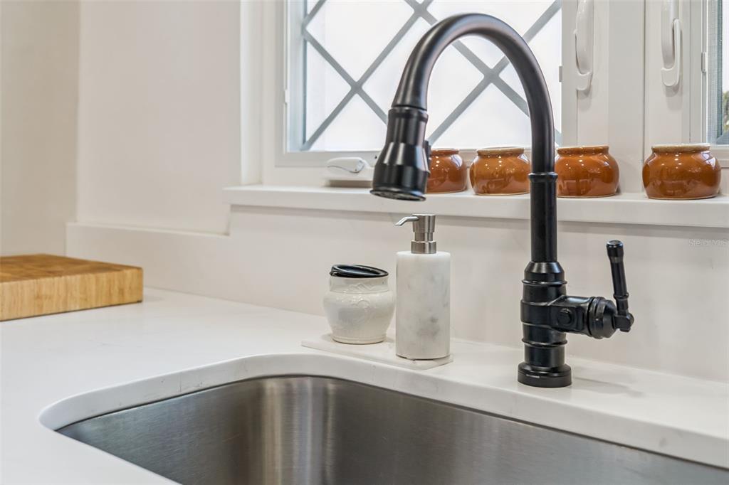 A kitchen sink with a black faucet and soap dispenser sits on a white countertop — 1304 SANTA ROSA COURT, THE VILLAGES, FL