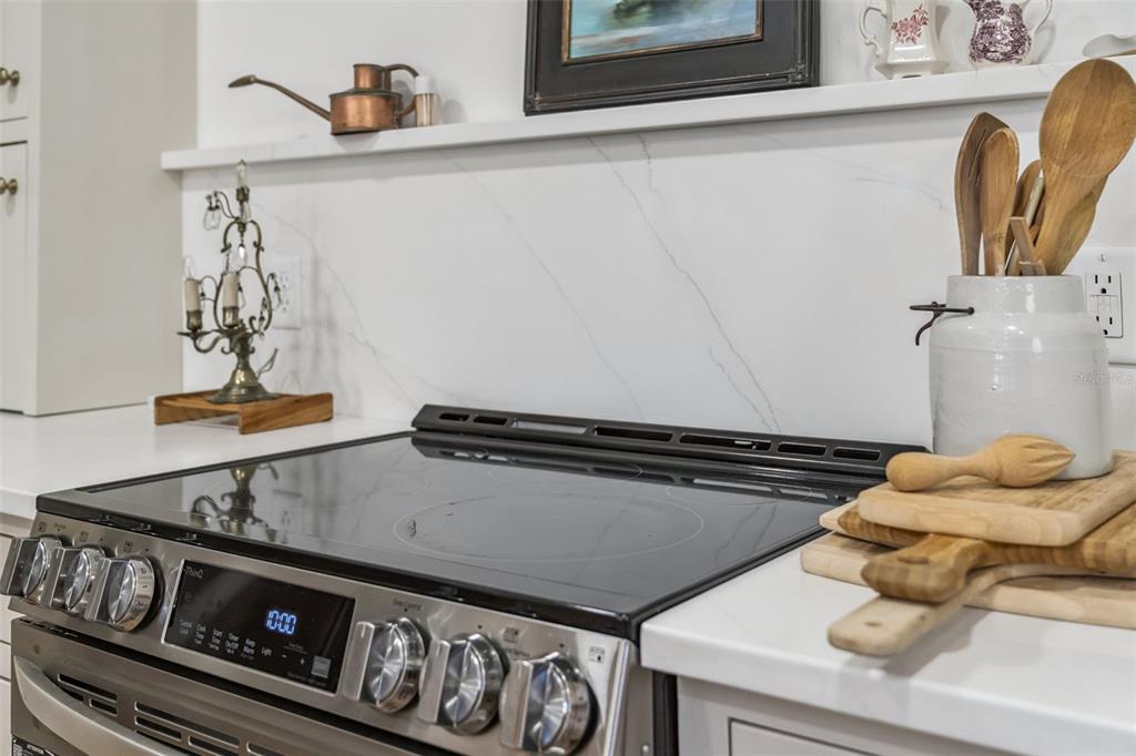 A stainless steel electric range sits against a white marble backsplash in a kitchen — 1304 SANTA ROSA COURT, THE VILLAGES, FL