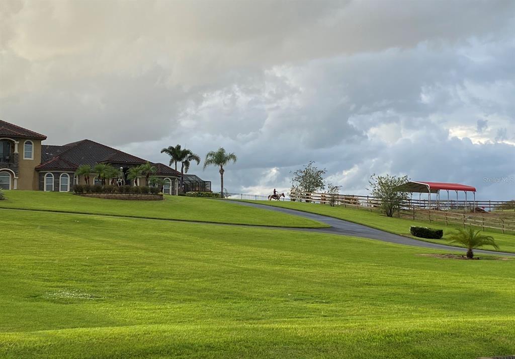 A person rides a horse on a grassy lawn near a house and a carport — 3700 SNYDER ROAD, SEBRING, FL