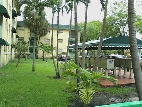 A grassy courtyard features palm trees and a covered outdoor area with mailboxes — 666 W 81st St # 124, Hialeah FL 33014, HIALEAH, FL