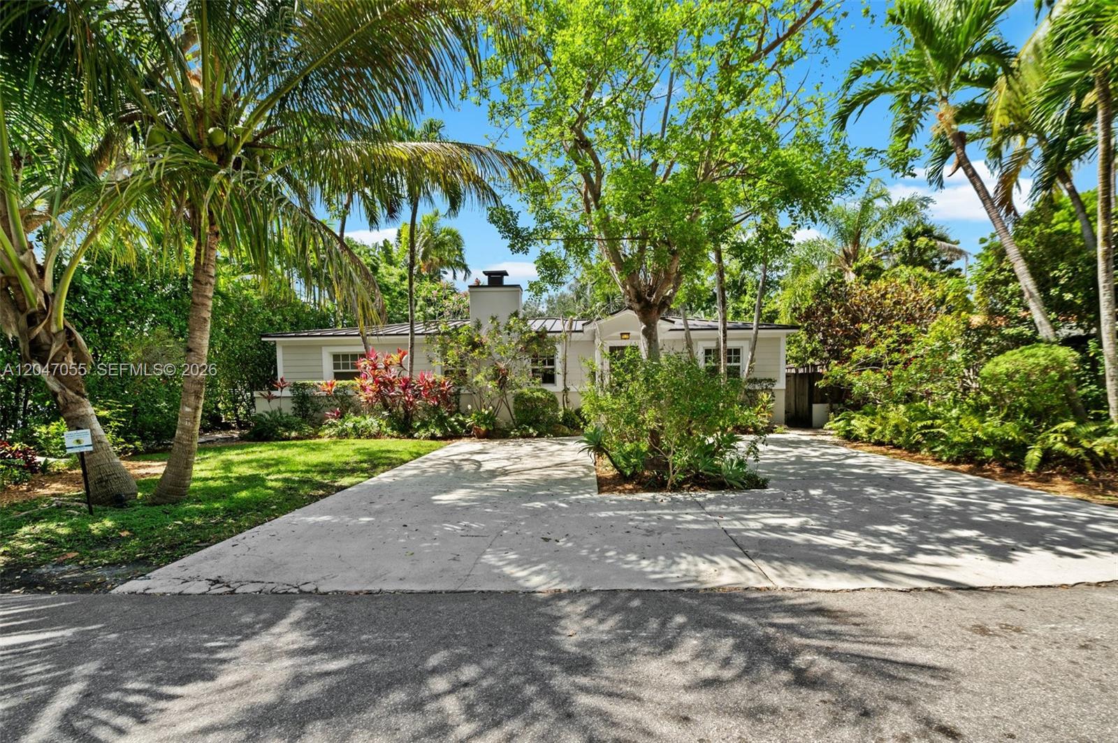 A single-story house with a concrete driveway and lush landscaping under a clear blue sky — 4054 Bonita Ave, Miami FL 33133, MIAMI, FL