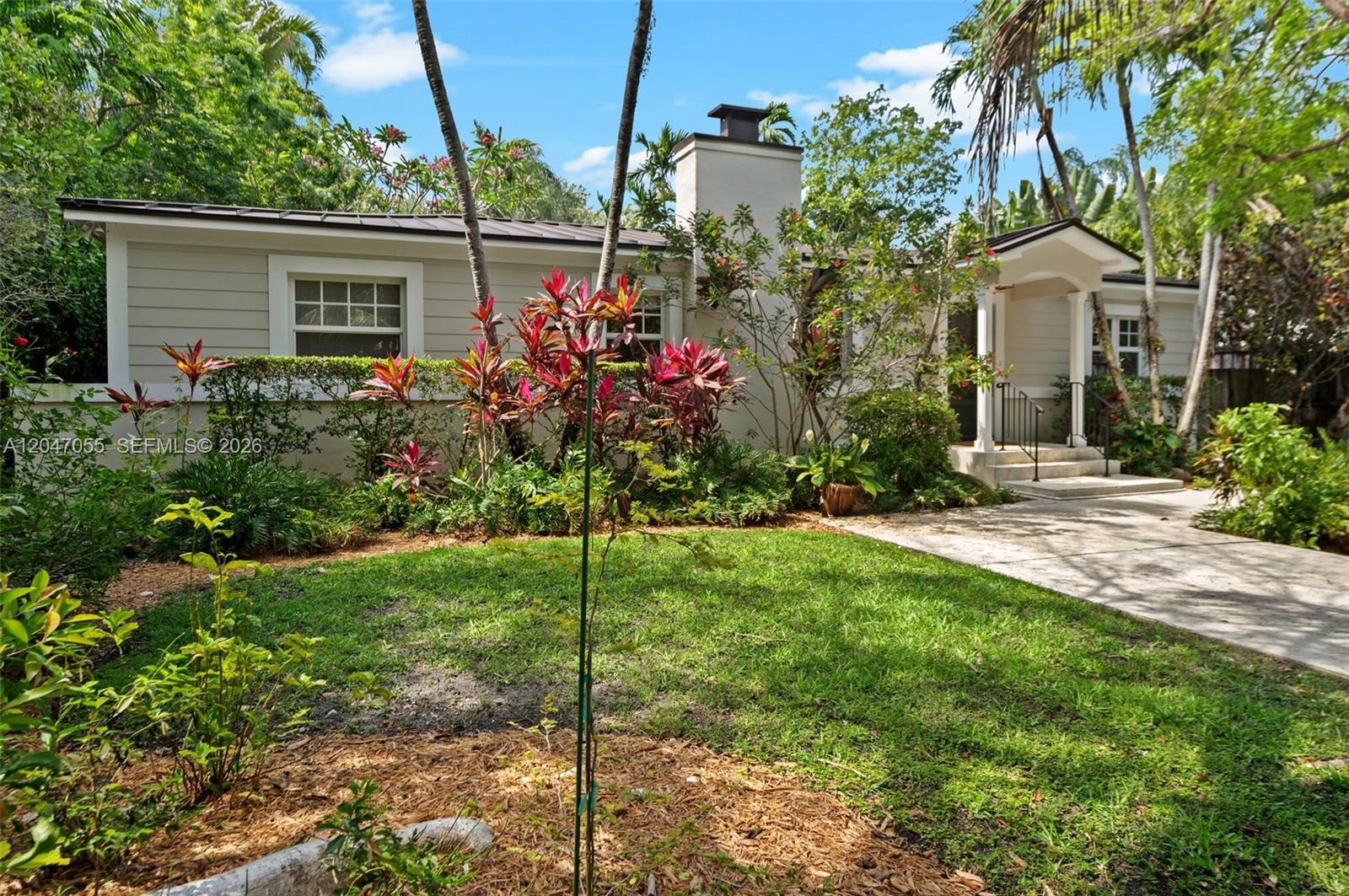A single-story house with light-colored siding, a chimney, and a landscaped front yard — 4054 Bonita Ave, Miami FL 33133, MIAMI, FL
