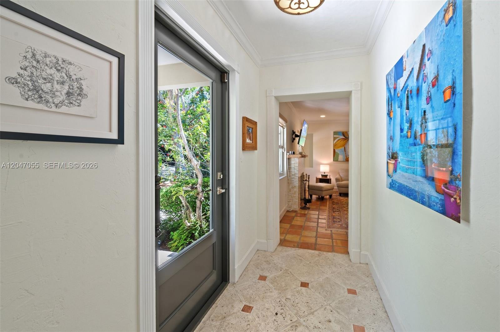 An entryway with light stone flooring leads to a living area with terracotta tile floors — 4054 Bonita Ave, Miami FL 33133, MIAMI, FL