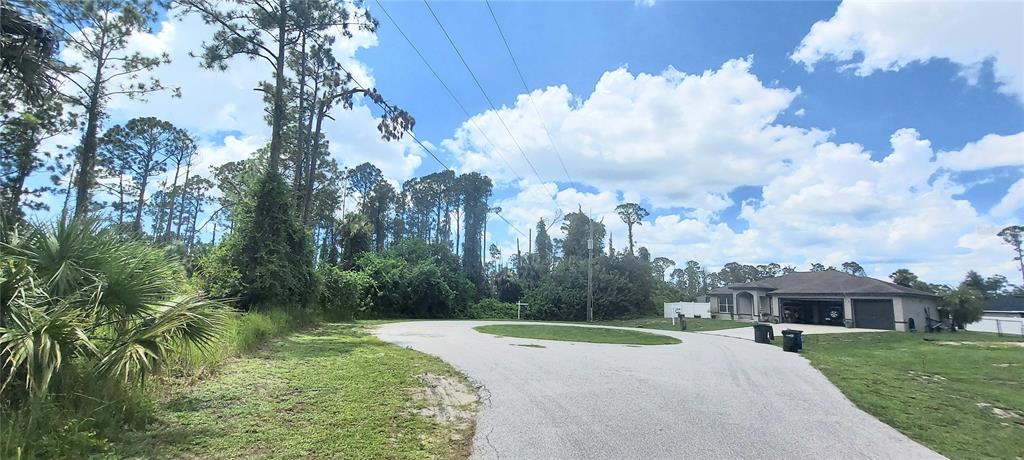 A paved cul-de-sac leads to a residential house surrounded by trees and grassy areas — GOURMET ROAD, NORTH PORT, FL