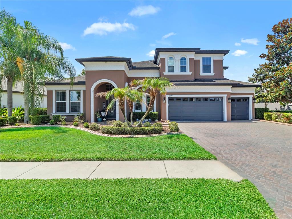 A two-story house with a brown stucco exterior, arched entryway, and a brick paver driveway — 32430 SILVERCREEK WAY, WESLEY CHAPEL, FL