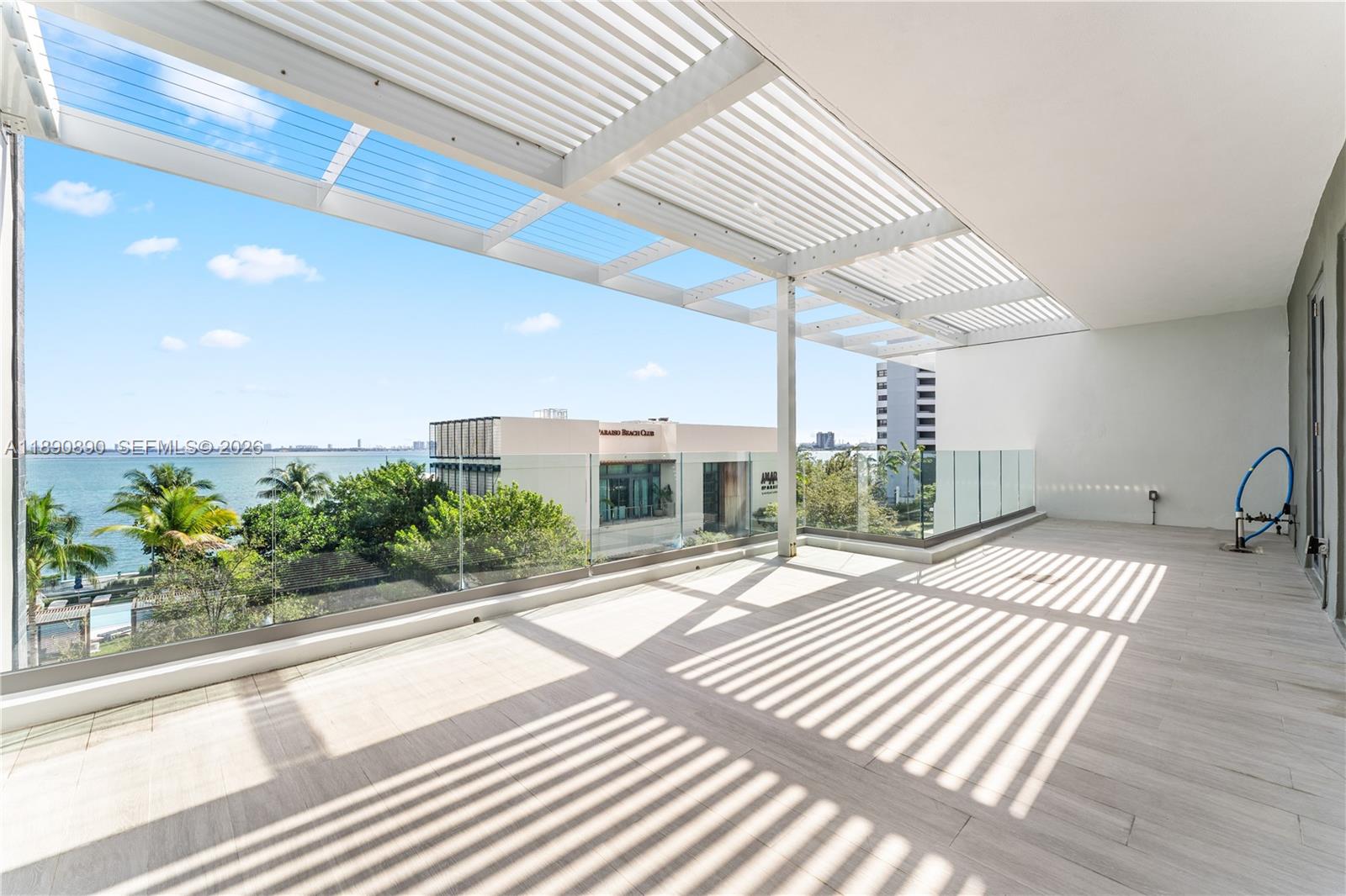 A spacious balcony features a slatted pergola, glass railings, and views of the ocean — 650 NE 32nd St, Miami FL 33137, MIAMI, FL