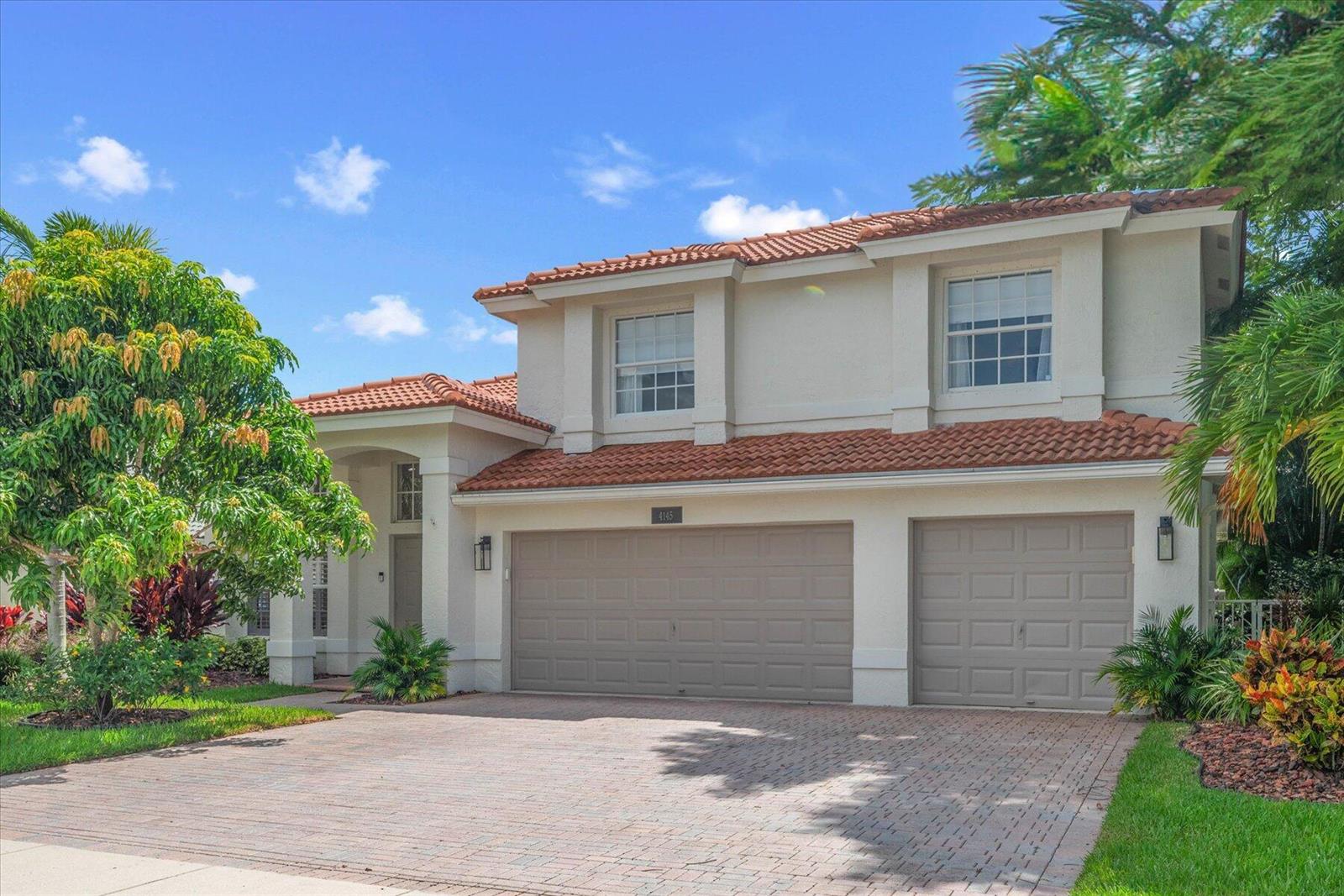 A two-story house with a tile roof, beige stucco exterior, and a three-car garage — 4145 Bahia Isle Circle, Wellington FL 33449, WELLINGTON, FL