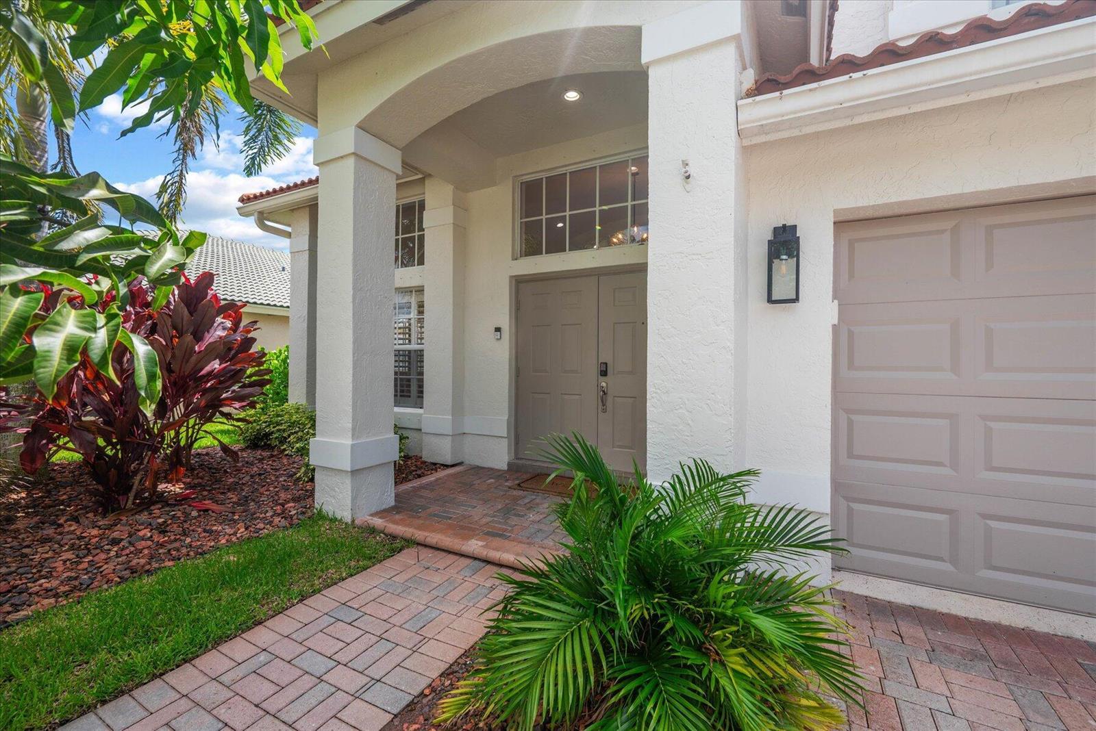 A paved walkway leads to the double front doors of a house with a garage — 4145 Bahia Isle Circle, Wellington FL 33449, WELLINGTON, FL