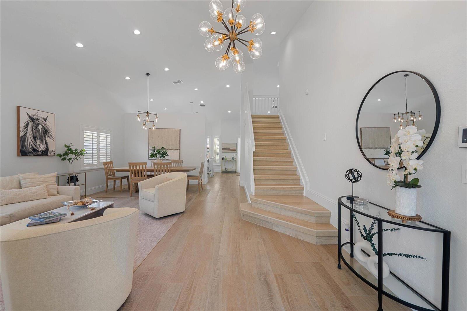 A bright open-concept living and dining area features light wood flooring and a central staircase — 4145 Bahia Isle Circle, Wellington FL 33449, WELLINGTON, FL
