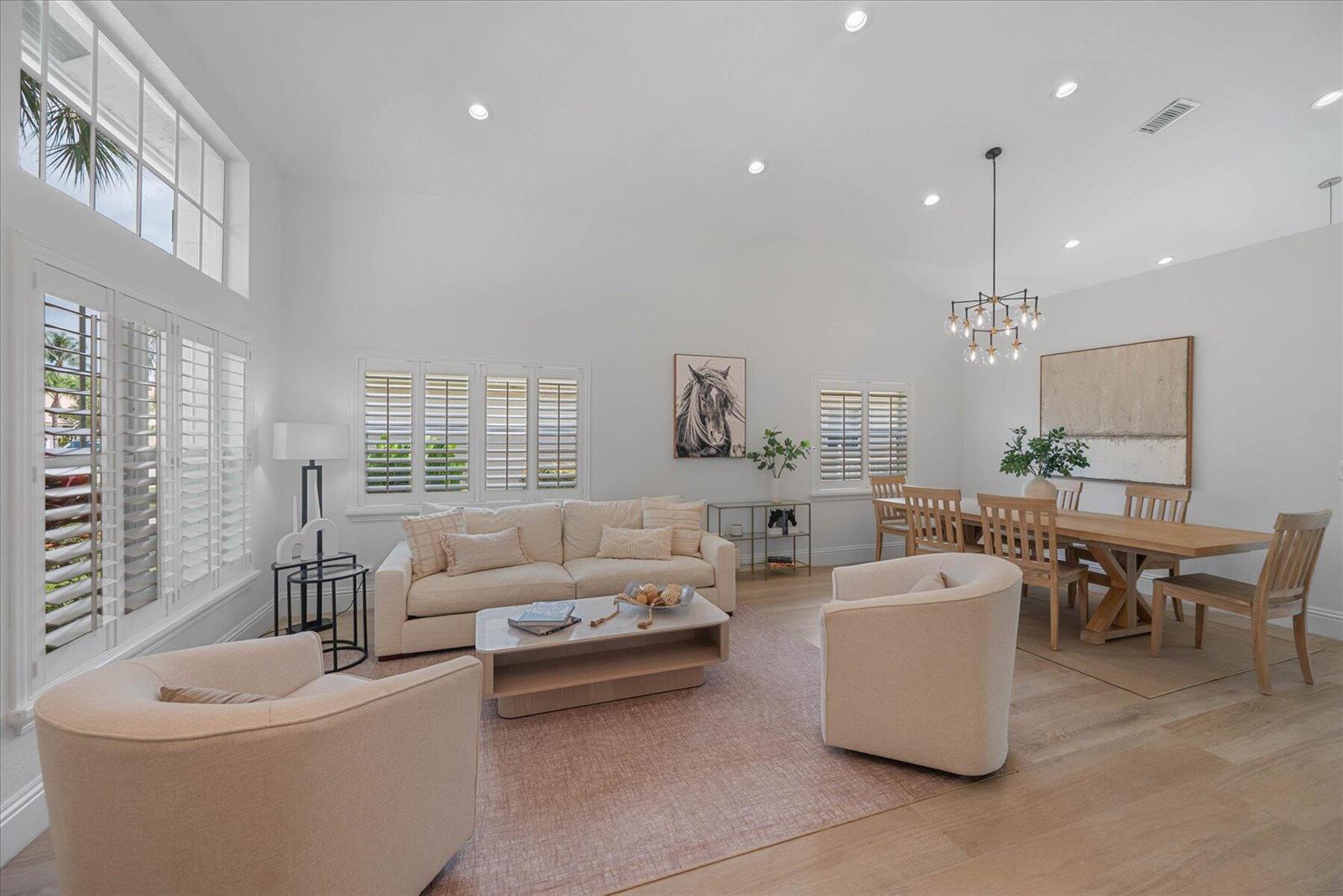 A bright, open-concept living and dining area features light wood floors, white walls, and neutral furniture — 4145 Bahia Isle Circle, Wellington FL 33449, WELLINGTON, FL