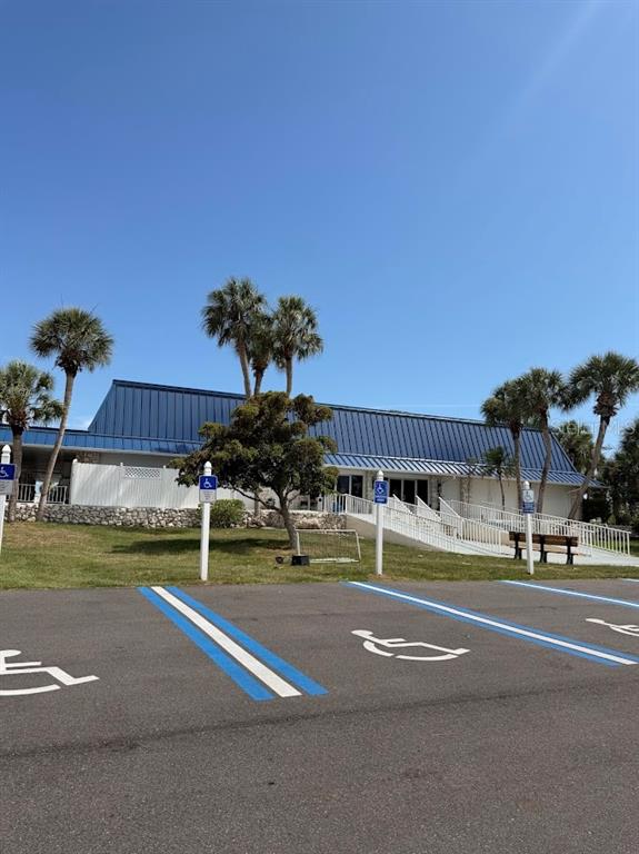 A blue-roofed building with a white fence and palm trees sits behind a parking lot — 833 JOLANDA CIRCLE, VENICE, FL