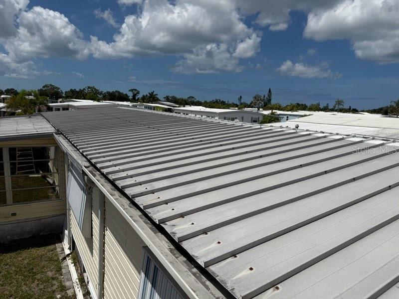 An elevated view of a metal roof on a manufactured home under a cloudy sky — 833 JOLANDA CIRCLE, VENICE, FL