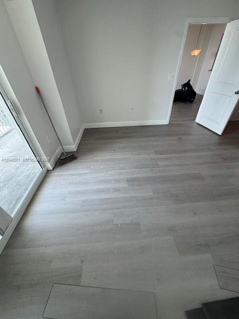 An empty room features light-colored wood-look flooring, white walls, a sliding glass door, and a doorway — 1250 S Miami Ave # 1713, Miami FL 33130, MIAMI, FL